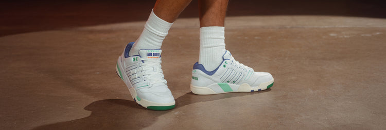 Close-up of man's feet in K-Swiss sneakers with green and blue accents and white athletic socks