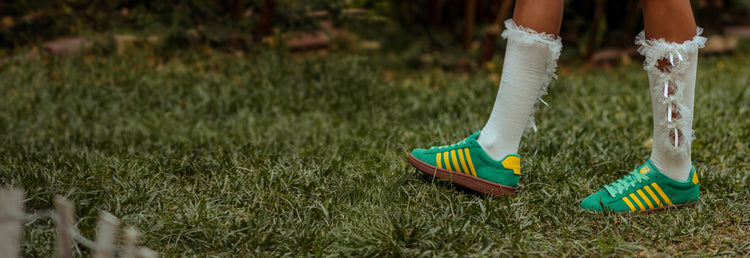 K-Swiss Court Tiebreak II sneakers in green and yellow worn by someone standing on grass