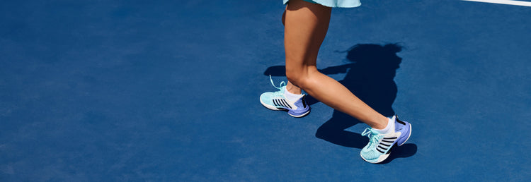 Image of a woman's legs wearing K-Swiss pickleball shoes on a blue pickleball court