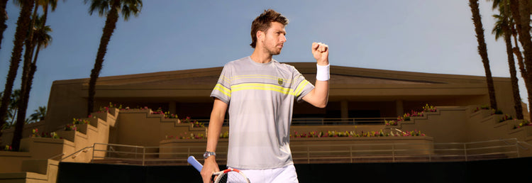 Cameron Norrie holding a tennis racket and pumping a fist in celebration while wearing K-Swiss clothing