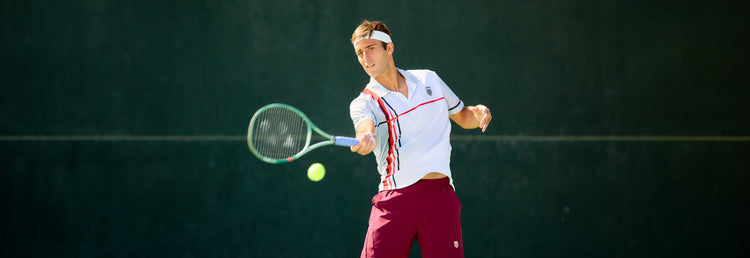 Tomas Etcheverry playing tennis while wearing K-Swiss clothing