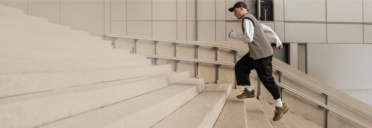 Person running up a flight of stairs in an urban environment while wearing the K-Swiss Tubes Lite RMX sneakers
