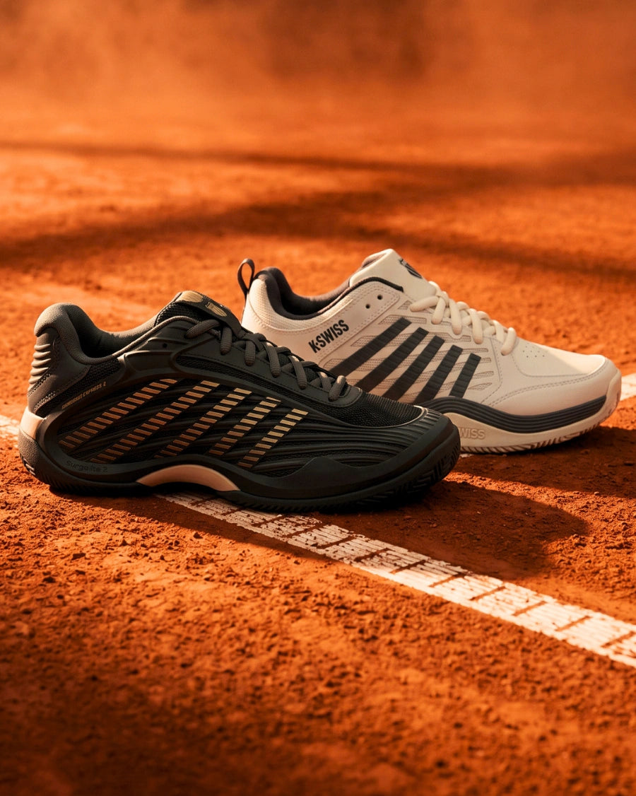 Black and white tennis shoes on a clay court