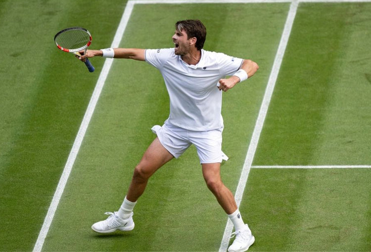 Cameron Norrie celebrating on a grass court while wearing K-Swiss clothing and shoes