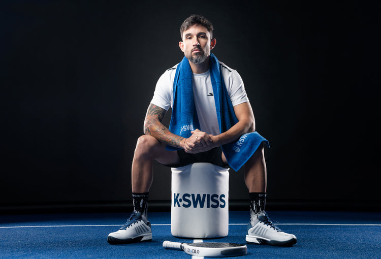 Sanyo Gutierrez sitting on a K-Swiss stool and wearing K-Swiss padel shoes