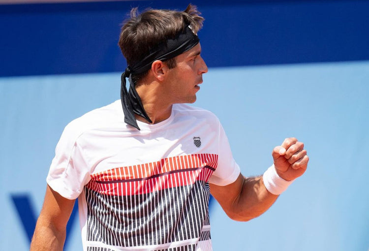 Tomas Etcheverry holding up a fist in celebration at a tennis tournament while wearing K-Swiss clothing