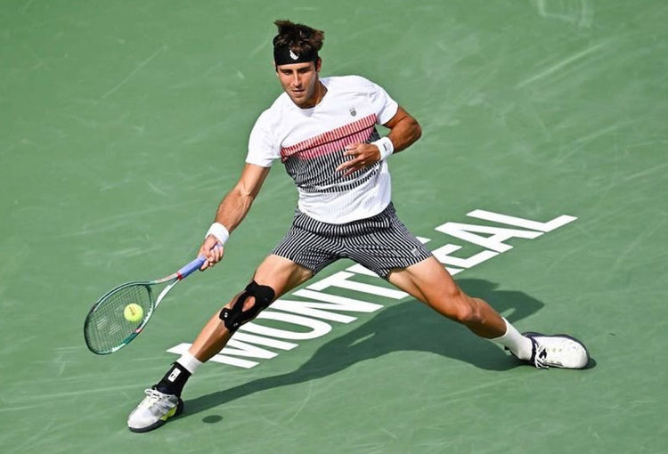 Tomas Etcheverry playing tennis while wearing K-Swiss clothing and shoes