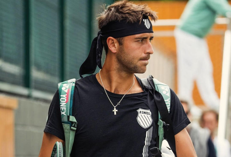 Tomas Etcheverry walking into a tennis match wearing K-Swiss clothing and a headband