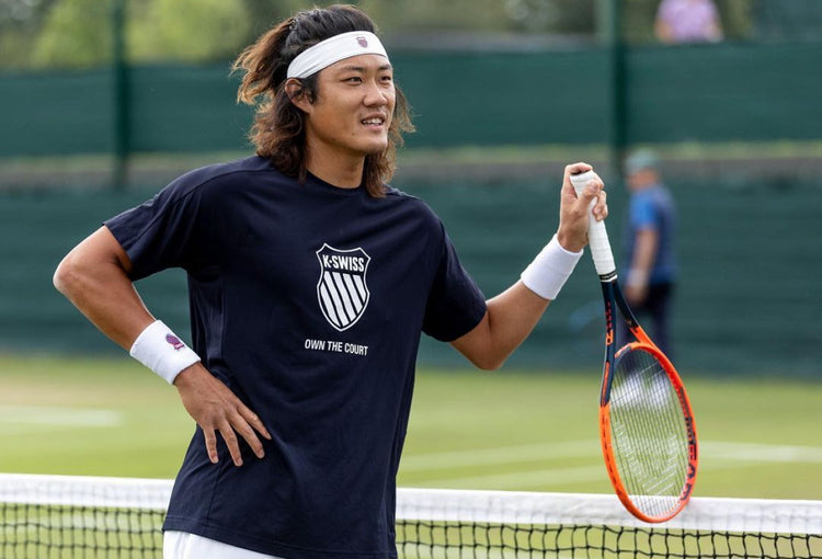 Zhizhen Zhang on a tennis court holding a tennis racket and wearing a K-Swiss t-shirt and headband