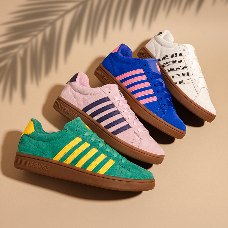 Four colorful sneakers on a beige background with a leaf shadow.