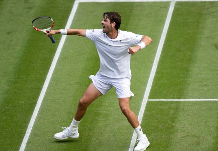 Cameron Norrie celebrating on a grass court while wearing K-Swiss clothing and shoes