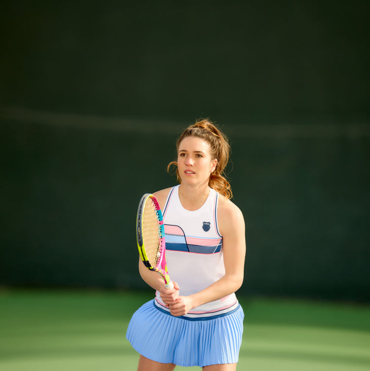 Woman with a tennis rack on a court in K-Swiss clothing