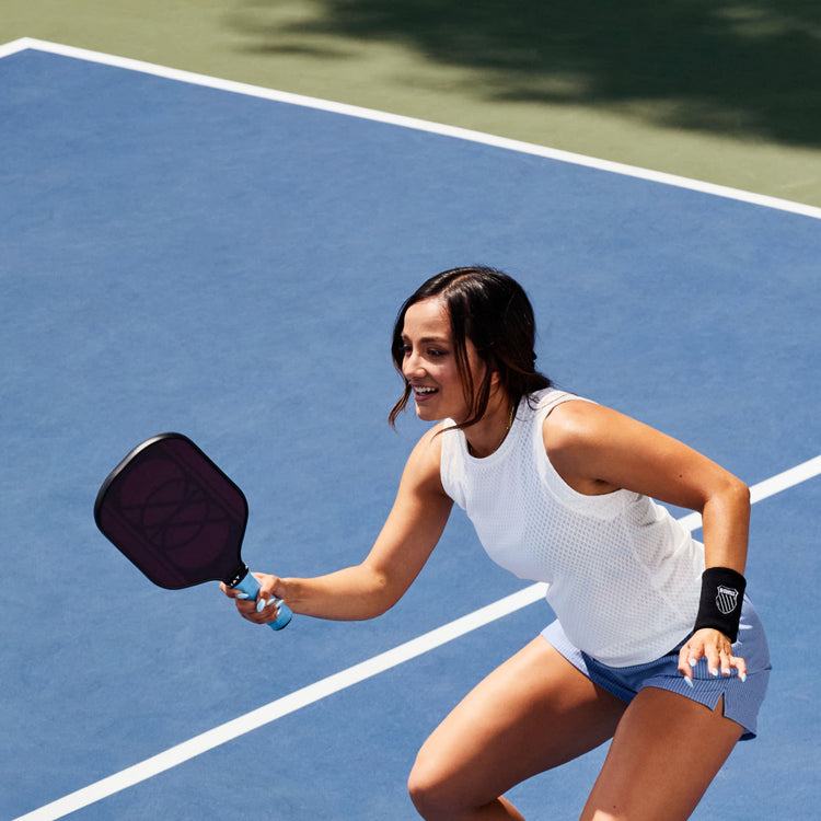 Image of a woman on a pickleball court wearing K-Swiss apparel and a wrist band