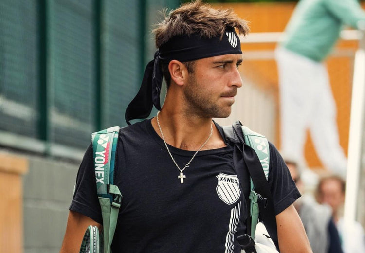 Tomas Etcheverry walking into a tennis match wearing K-Swiss clothing and a headband