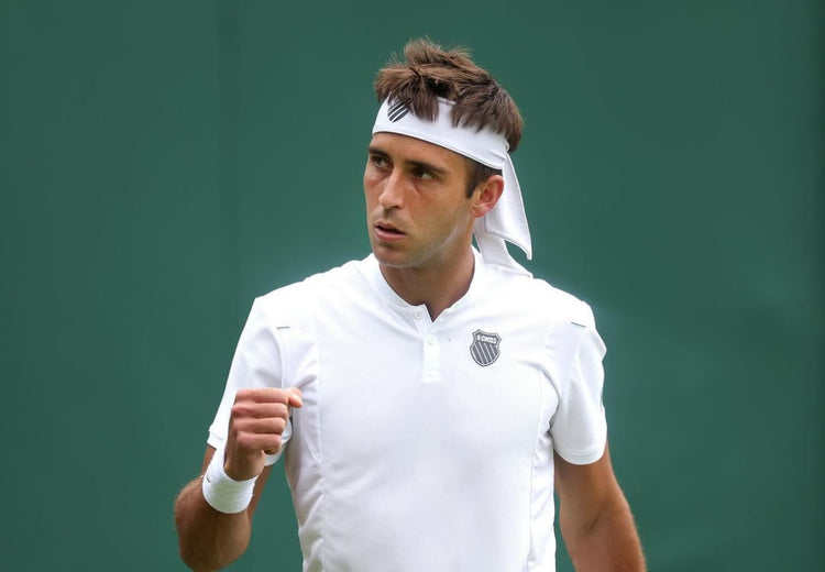 Tomas Etcheverry pumping a fist in celebration at a tennis match while wearing K-Swiss clothing and a headband