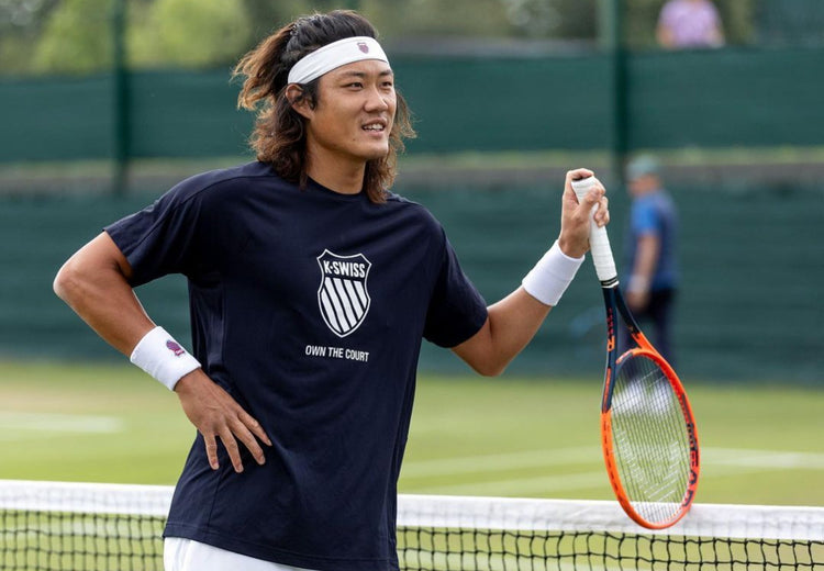 Zhizhen Zhang on a tennis court holding a tennis racket and wearing a K-Swiss t-shirt and headband